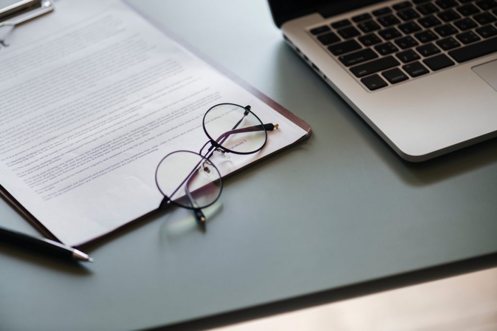 Photo of forms, glasses, and laptop (credit to rawpixel from Unsplash)